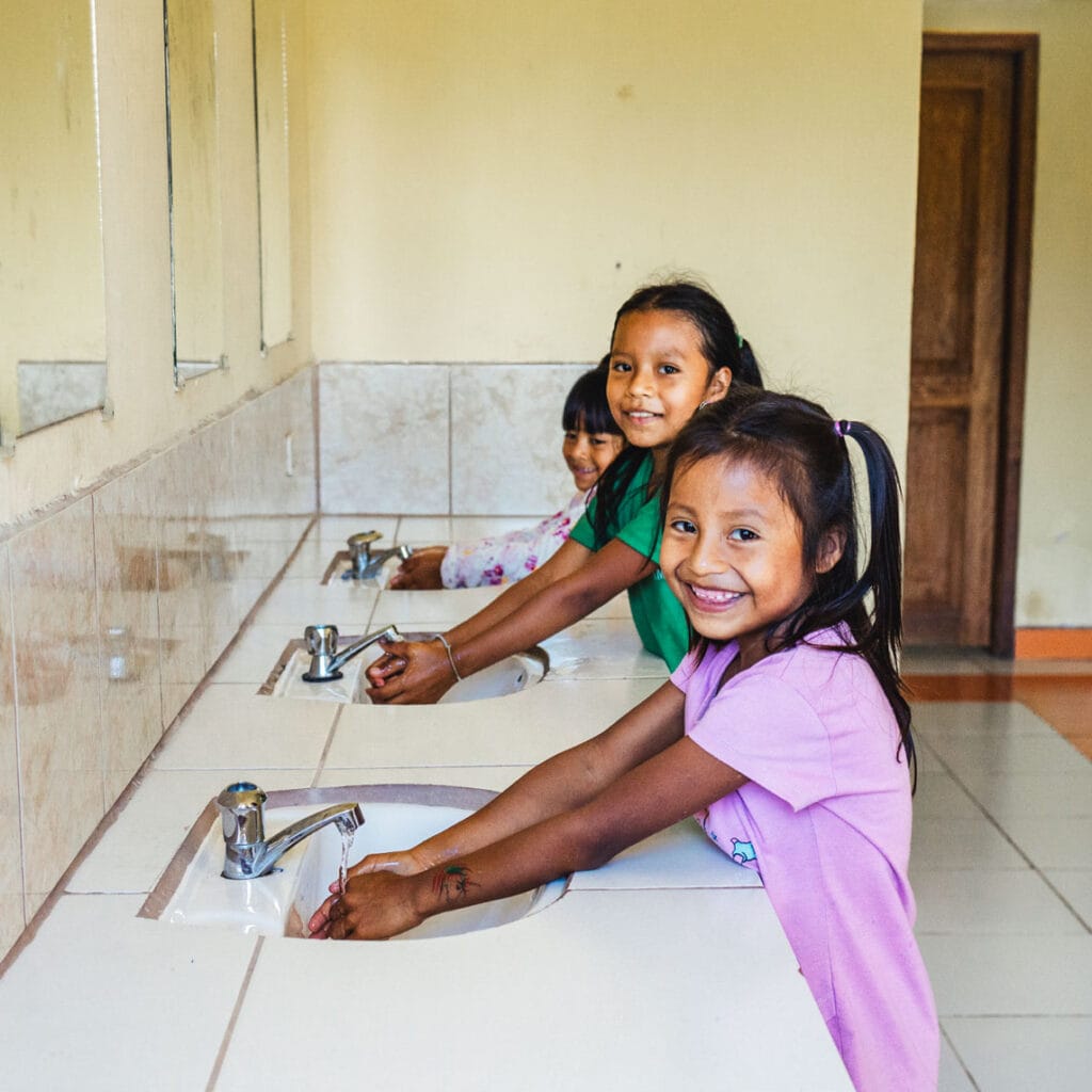 alt="Welttoiletten Tag 2022 Kinder beim Händewaschen und Hygiene lernen in einem Toilettenhäuschen in Ecuador