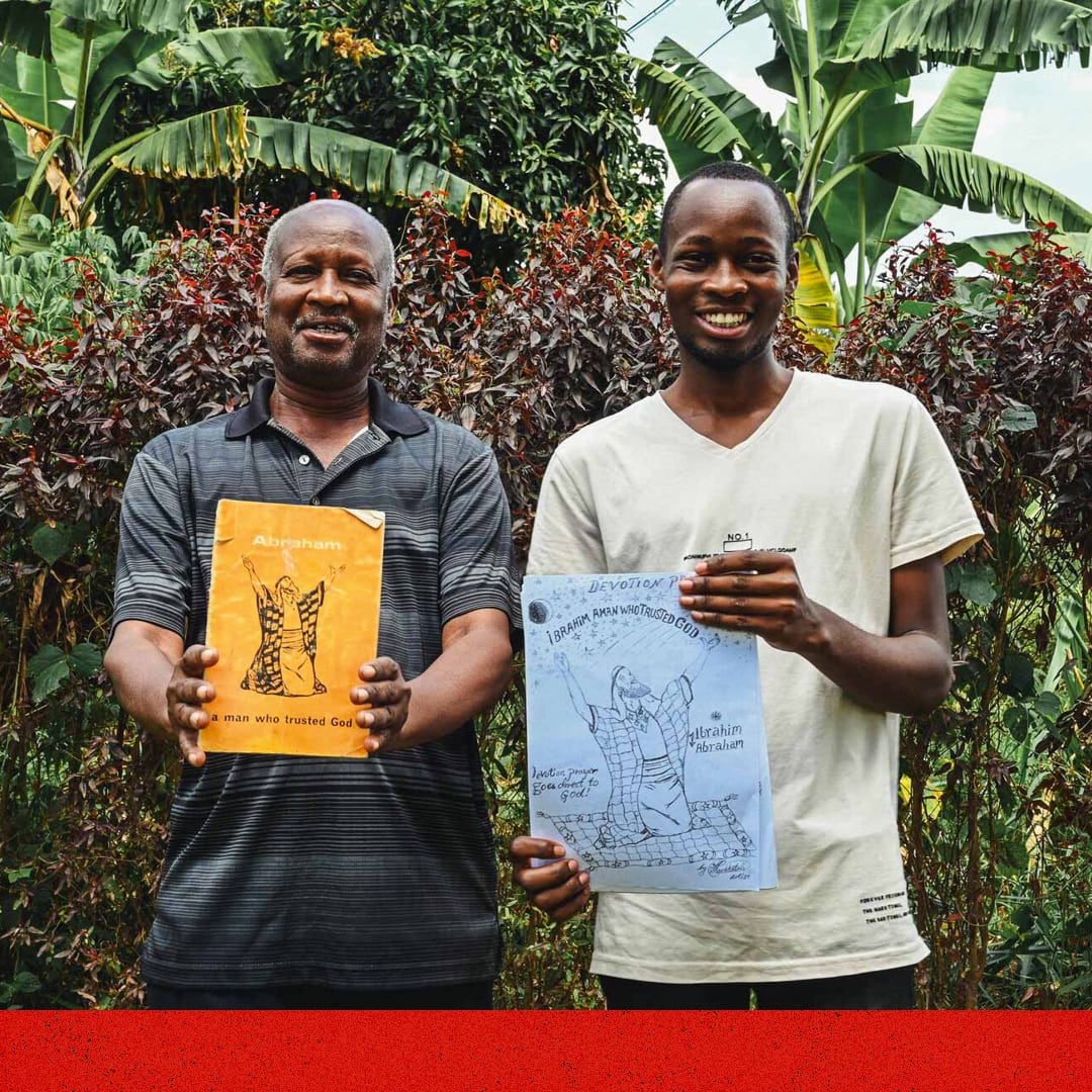 alt="Isaac mit Vater mit gezeichneten Bildern in Uganda Muskathlon Uganda 2023"