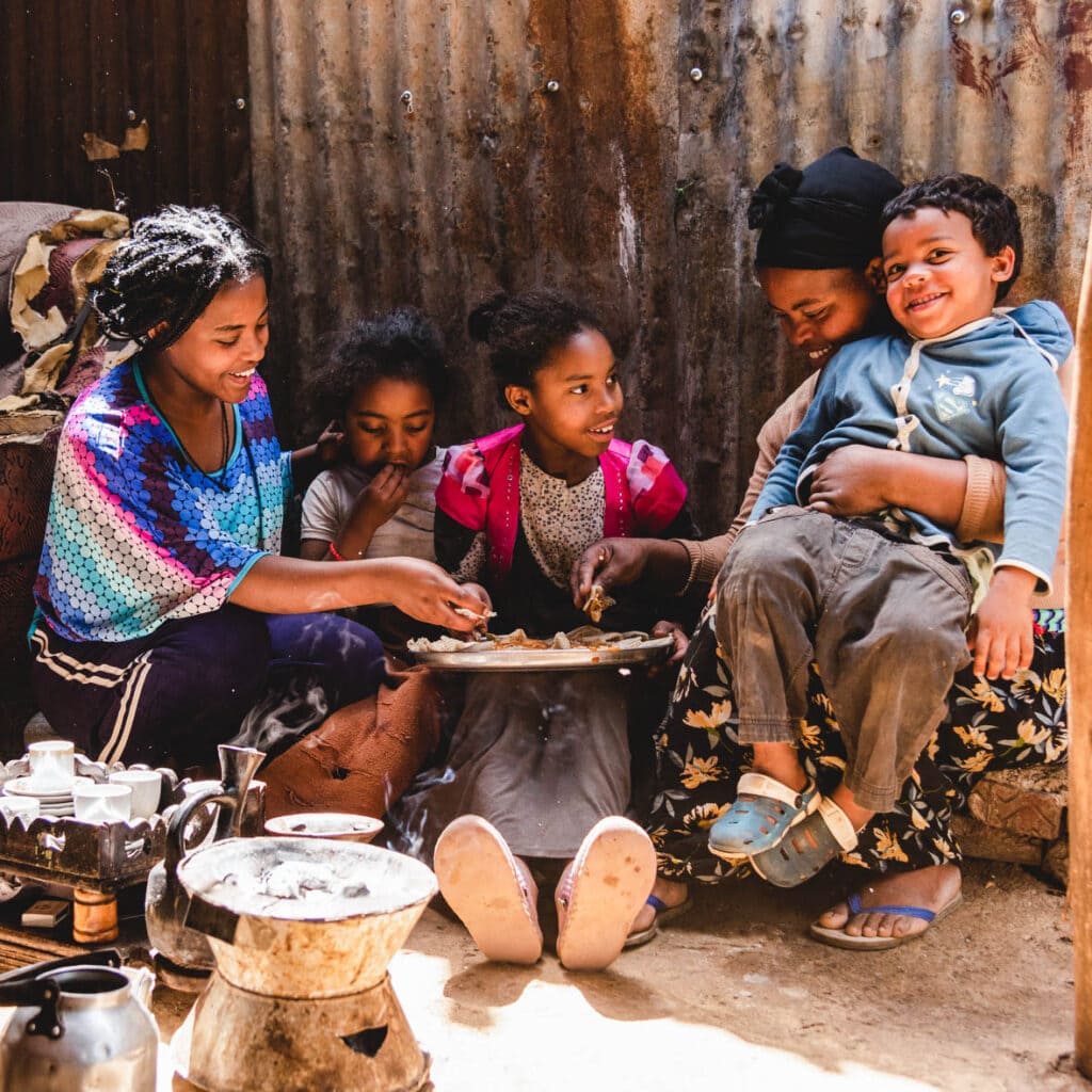 alt="Wie wirkt sich die Krise auf Kinder aus? Compassion Deutschland Lebensmittelhilfe | Kinder von Abijot vor Hütte am Essen"