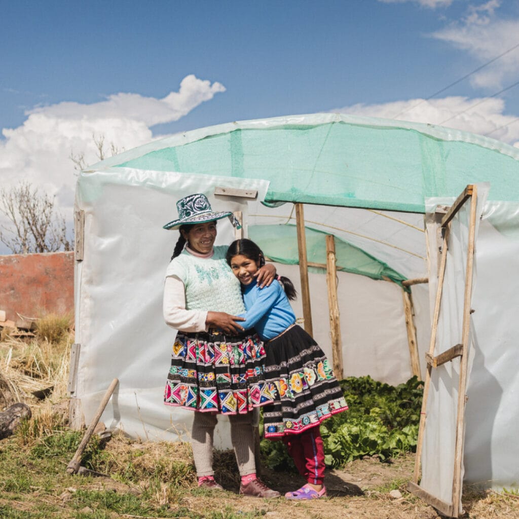 alt="Ein schönes Gewächshaus Alis und ihre Mutter in den peruanischen Anden vor ihrem Gewächshaus"