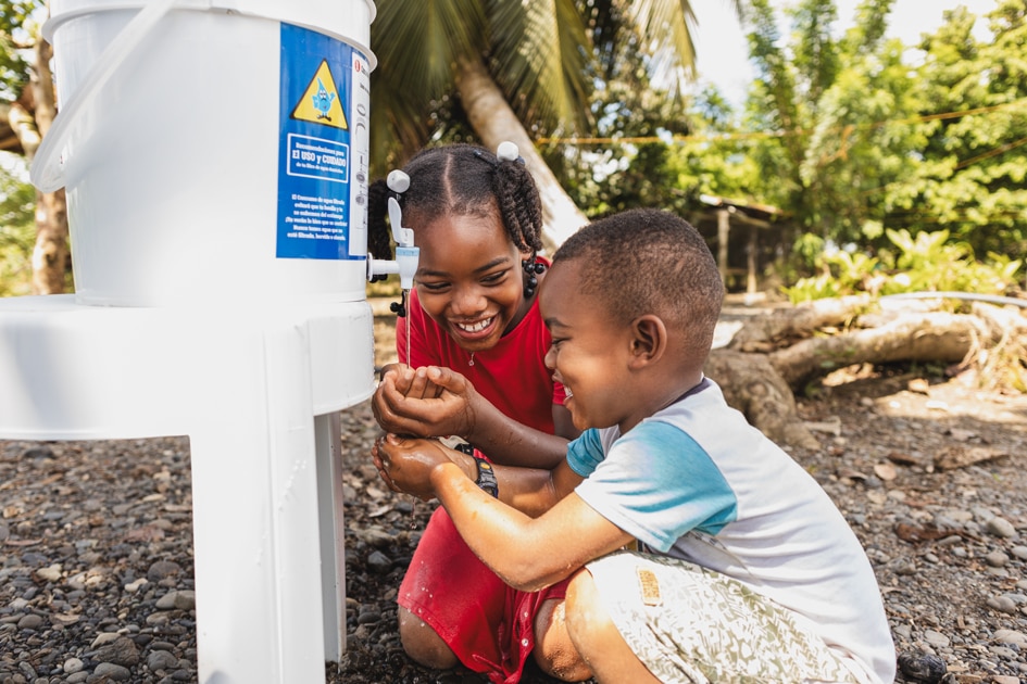 alt="Sauberes Wasser in Kolumbien, Esters Geschichte, Compassion Patenkind, Ester und ihr Freund freuen sich über Wasser, Compassion Deutschland"