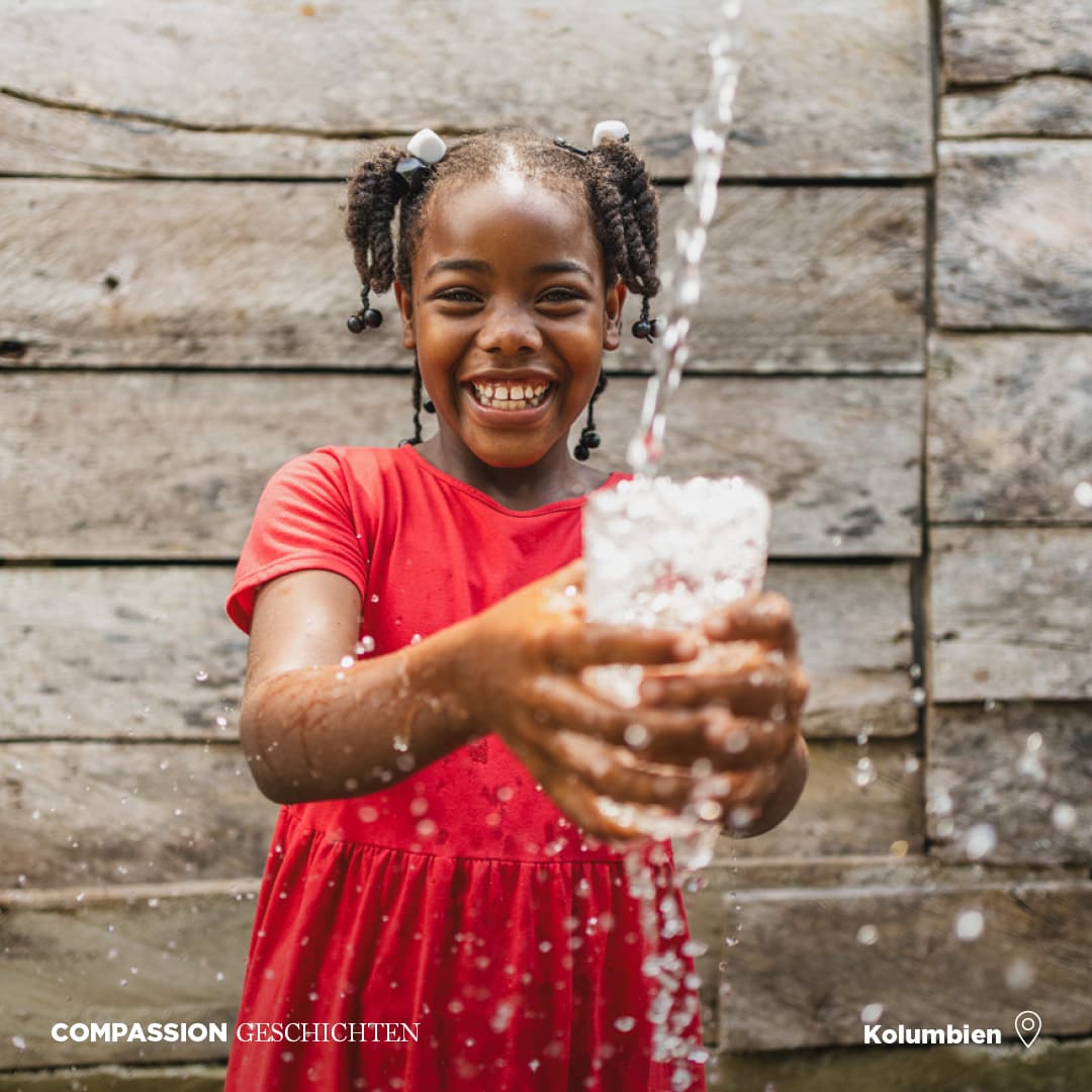 alt="Sauberes Wasser in Kolumbien, Esters Geschichte, Compassion Patenkind, Ester hält Wassergläser in ihren Händen, Compassion Deutschland"