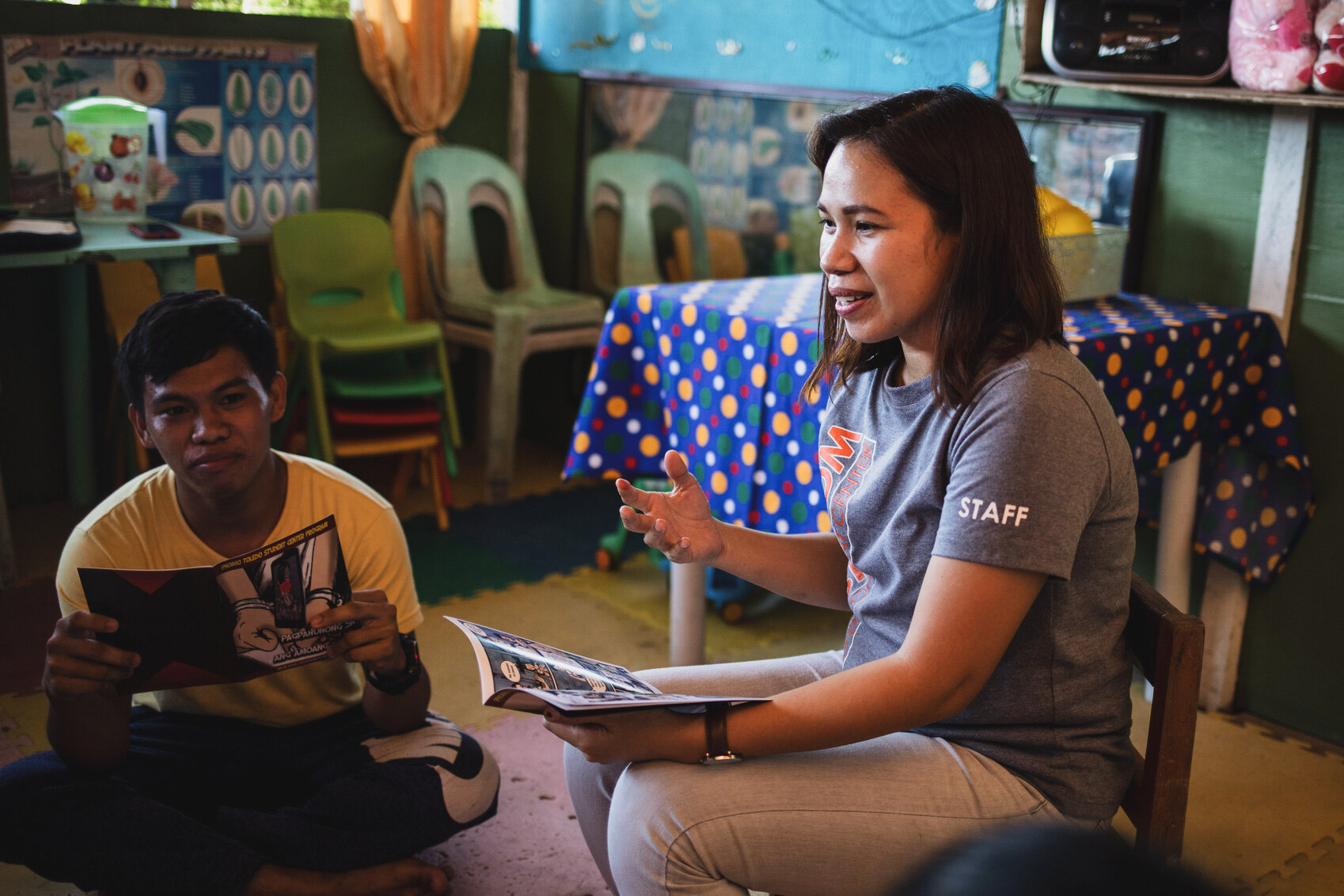 alt="Zwischen Holzkohle, Großstadt-Slum und Compassion-Kinderzentrum, Philippinen, Compassion Deutschland, Leiterin Kinderzentrum mit Kind am Buch lesen"