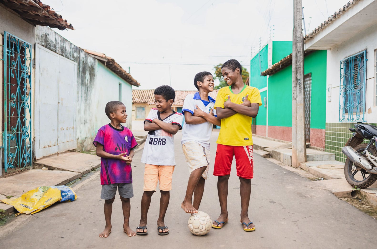 alt="Luis mit einem Fußball und Freunden auf der Straße, Luis`s Geschichte, Compassion Deutschland, Luís‘ Träume inmitten extremer Armut, Brasilien"