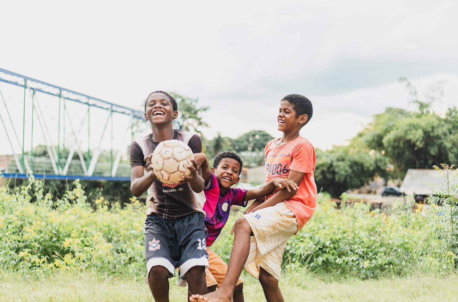 alt="Luis mit einem Fußball und Freunden auf einer Wiese, Luis`s Geschichte, Compassion Deutschland, Luís‘ Träume inmitten extremer Armut, Brasilien"