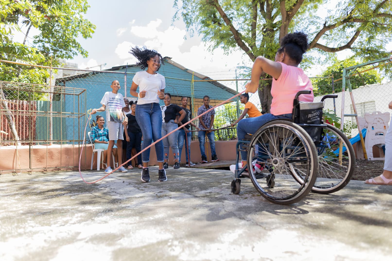 alt="Scarles Geschichte, Dominikanische Republik, ein Mädchen im Rollstuhl mit ihren Freundinnen am spielen im Garten, Compassion Deutschland"