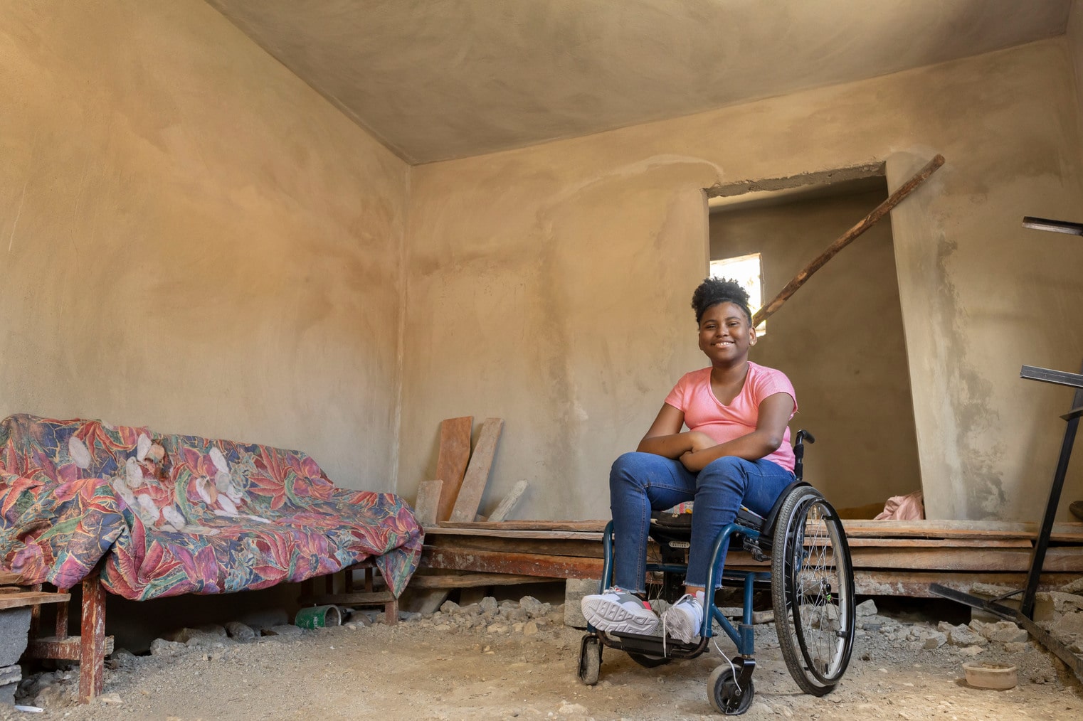 alt="Scarles Geschichte, Dominikanische Republik, ein Mädchen im Rollstuhl in dem Haus ihrer Mutter, Compassion Deutschland"