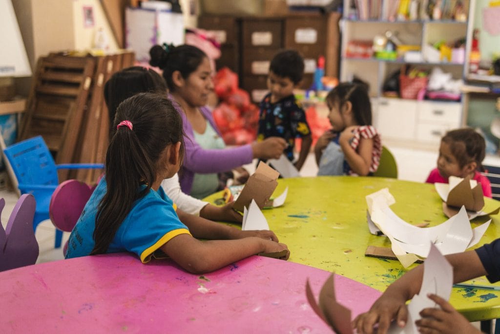 alt="Mitten in der Nacht, Muskathlon Home 2024, Philippinen, Gruppe von Kindern am Basteln an einem Tisch im Kinderzentrum"