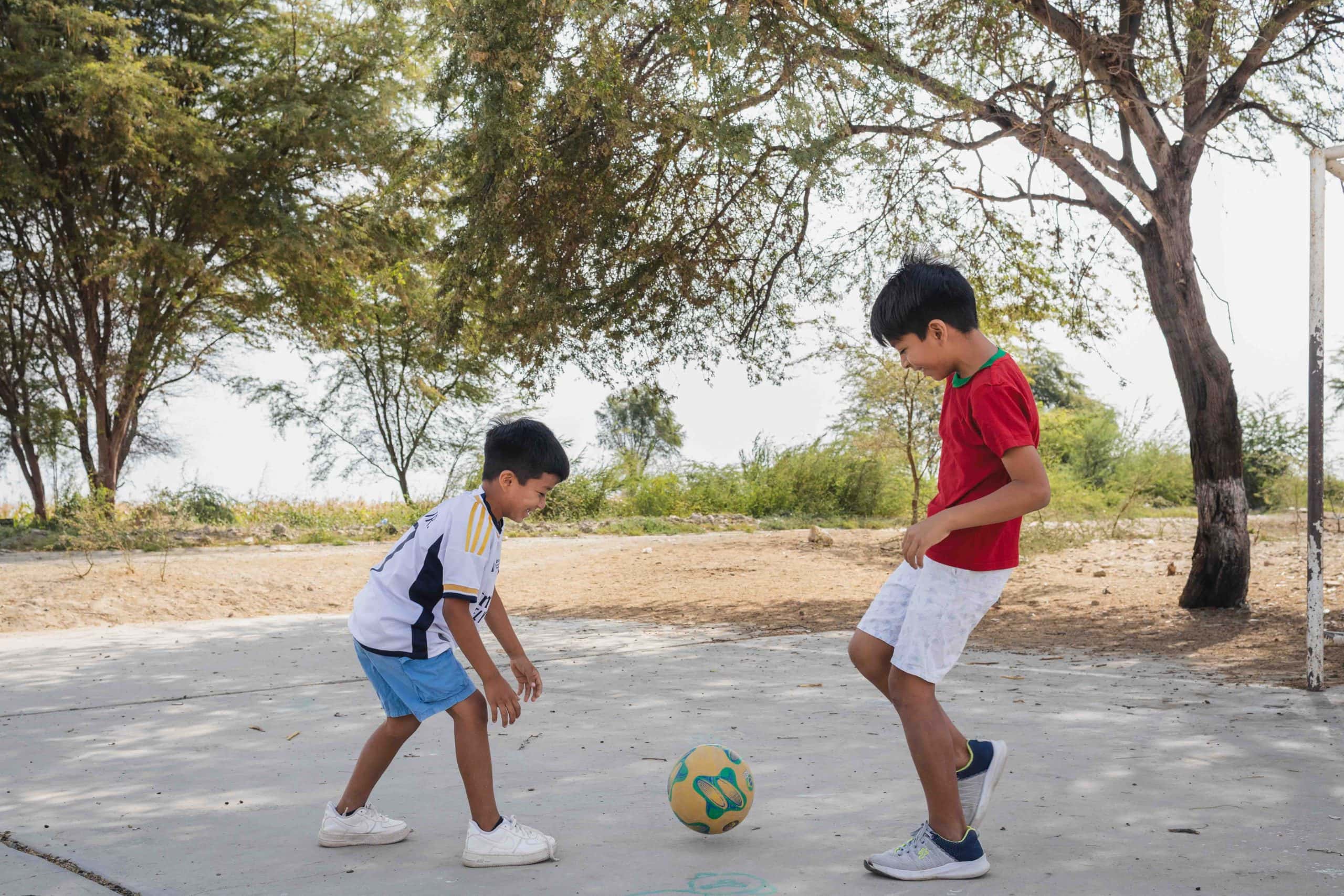 alt="Zwei Jungen in einem überfluteten Dorf in Peru spielen Fußball – Symbol für Hoffnung und Kindheit trotz Naturkatastrophen."