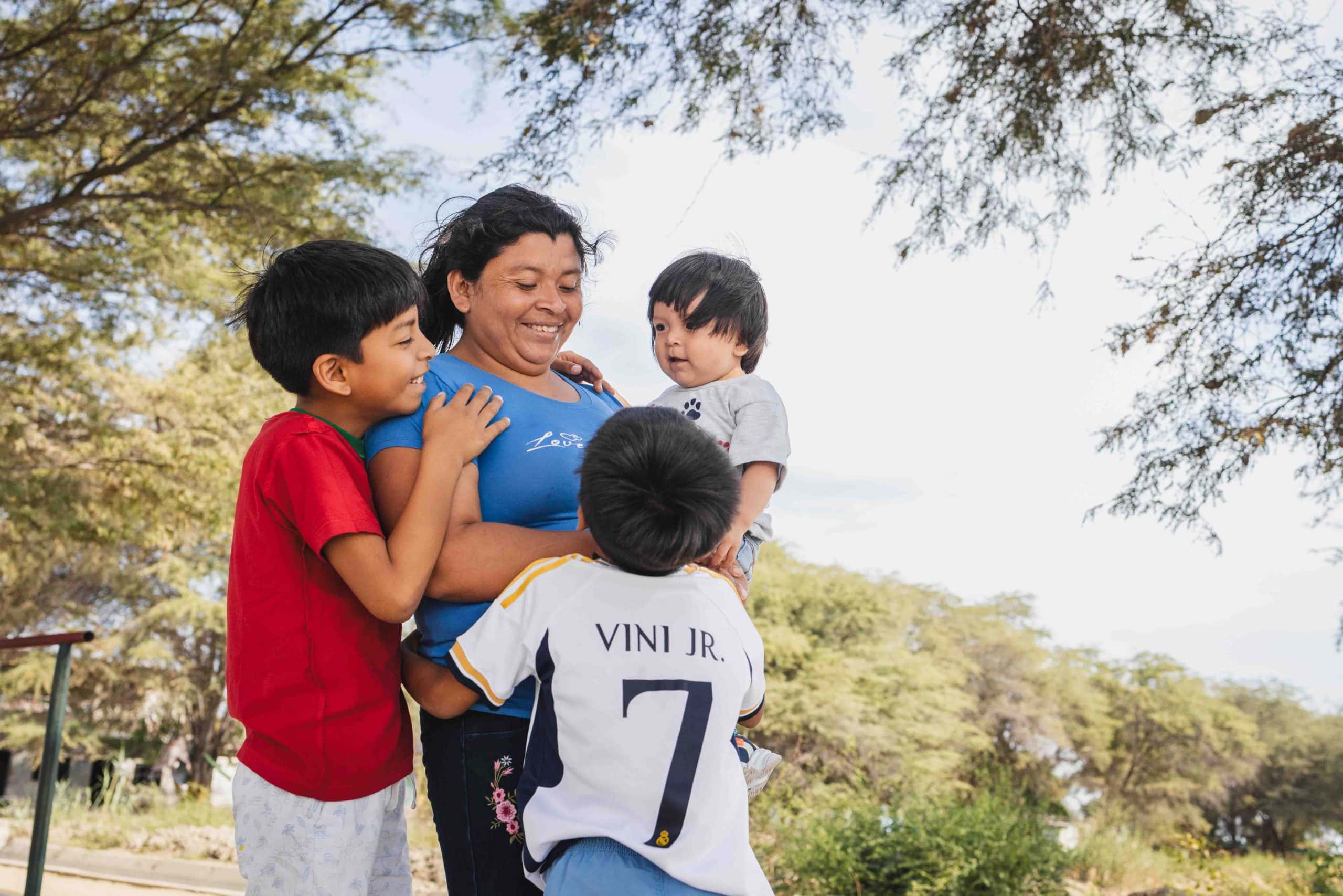 alt="Zwei Jungen stehen mit ihrer Mutter vor einem neu errichteten Haus in Peru – ein bewegender Moment des Neuanfangs nach einer Flutkatastrophe."