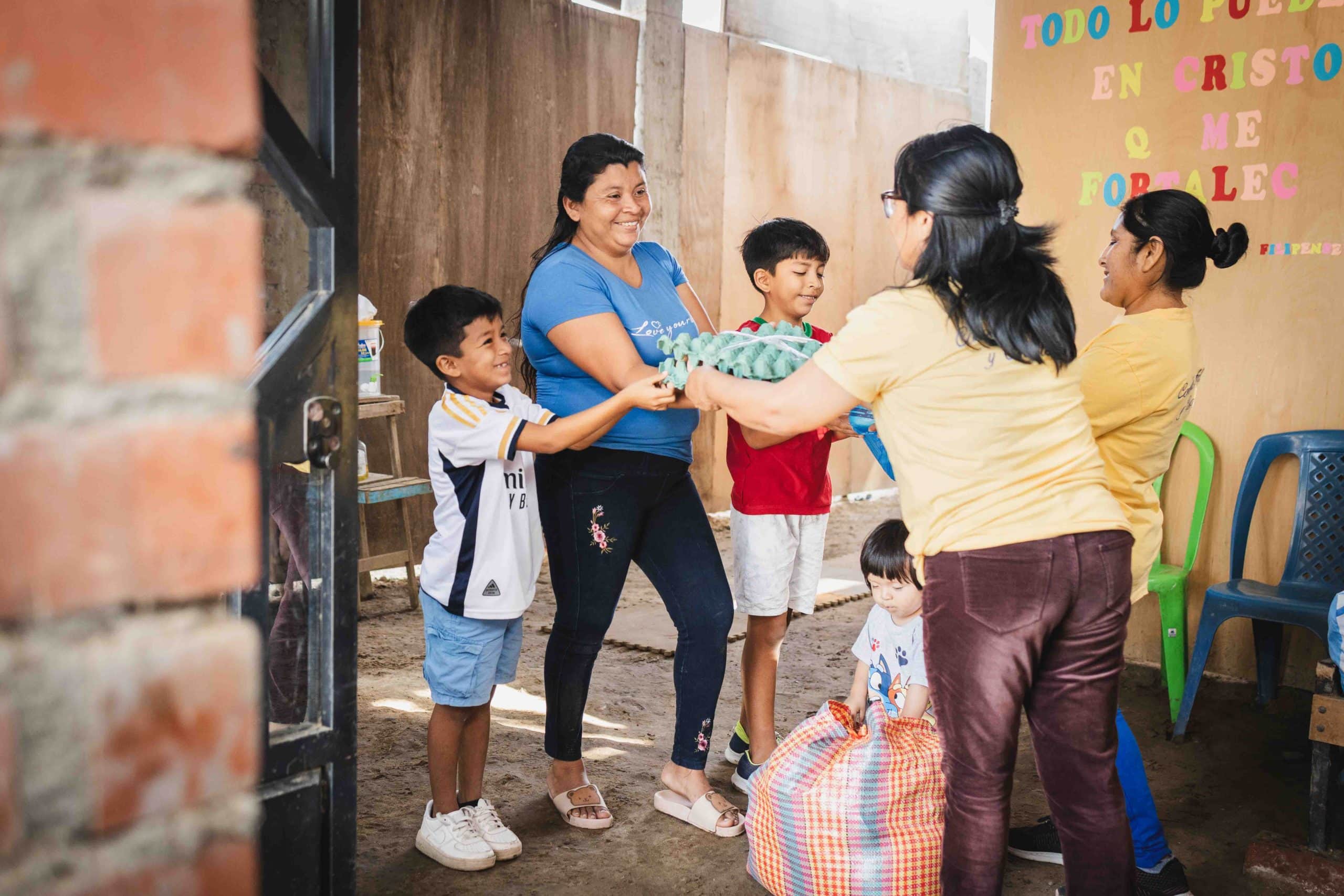 alt="Eine Mutter mit ihren beiden Söhnen nimmt dankbar Lebensmittelspenden entgegen – Unterstützung für eine Familie nach einer Naturkatastrophe in Peru."