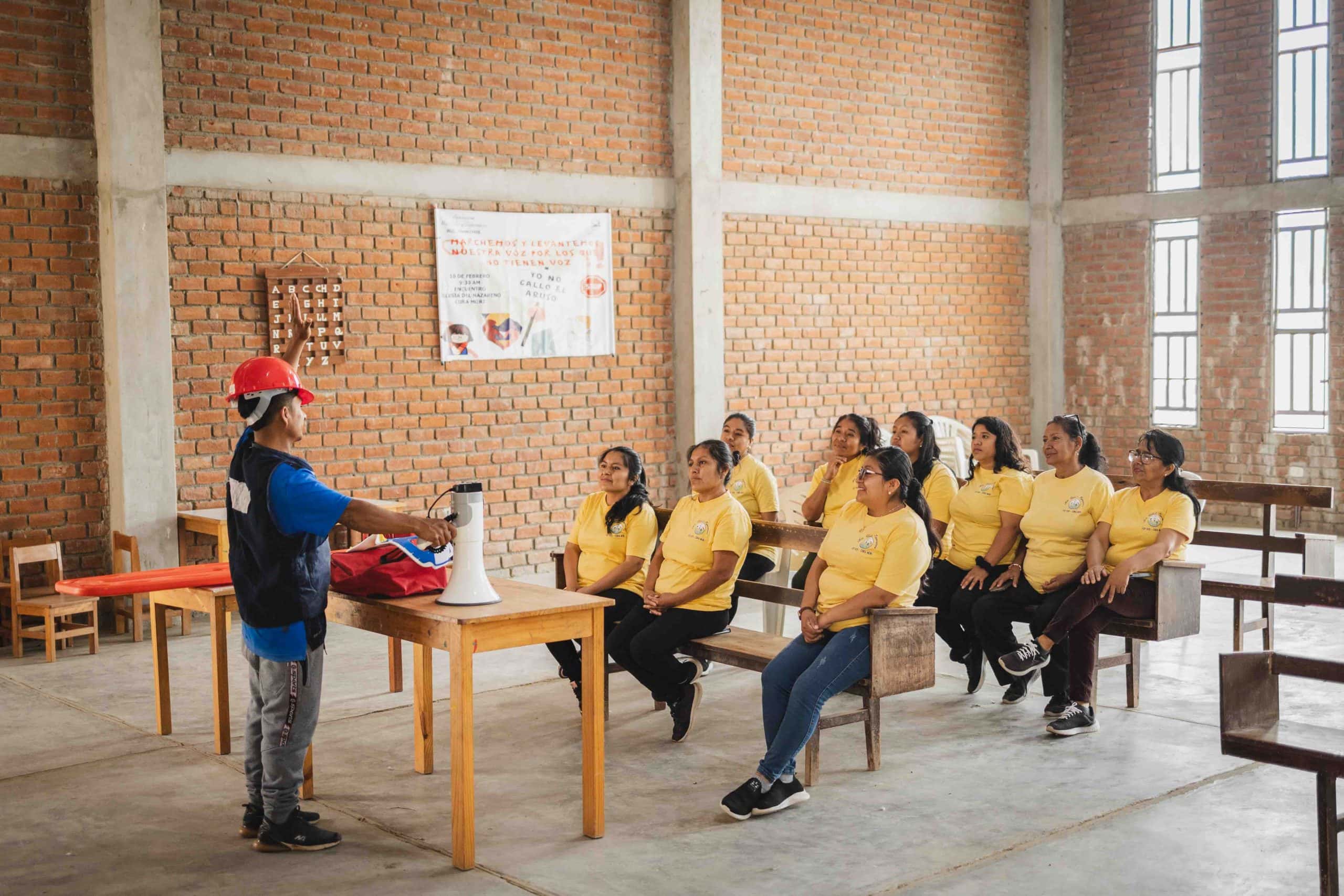 alt"=Eine Gruppe von Frauen steht lächelnd vor einem neu errichteten Haus in Peru – Zeichen für Gemeinschaft, Wiederaufbau und Hoffnung nach einer Flutkatastrophe."