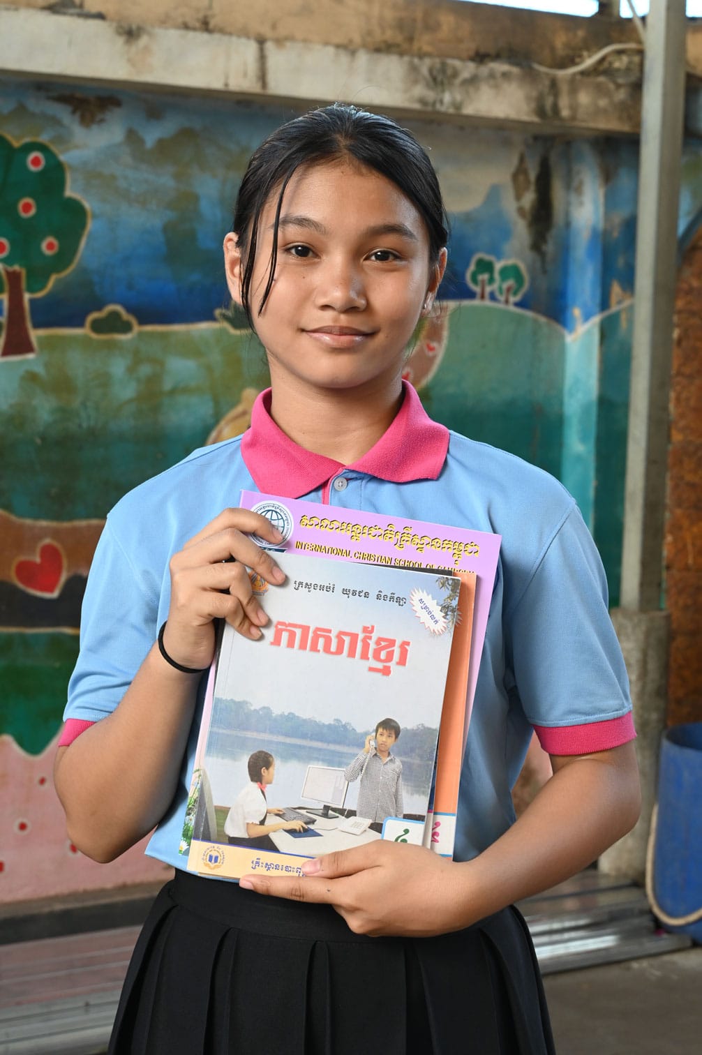 alt="zurück in die Schule, Compassion Deutschland, MÄdchen hält Buch in der Hand"