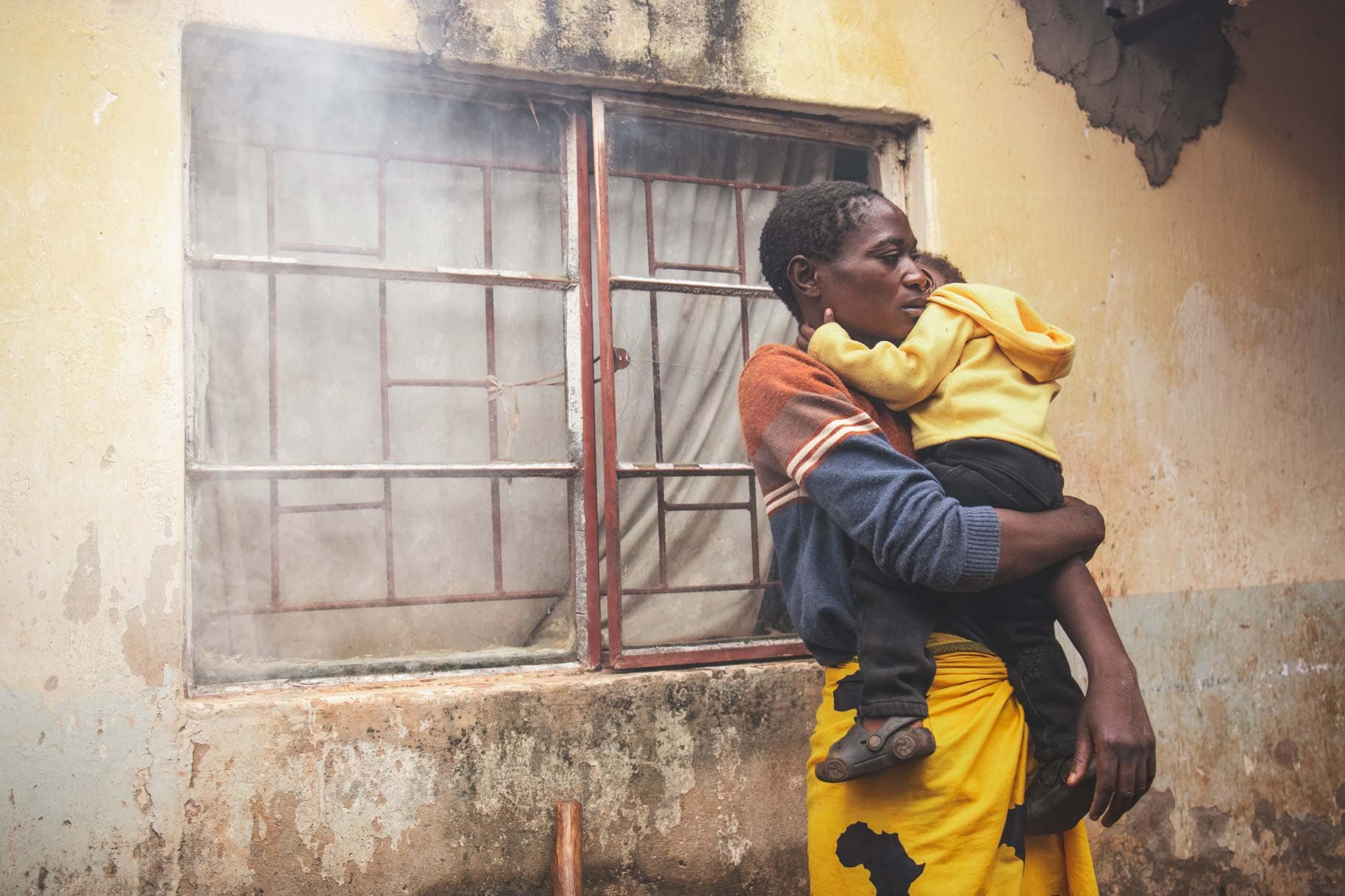 alt="Sorgende Mutter mit Kind vor einem alten Haus in Kenia., Compassion Deutschland"