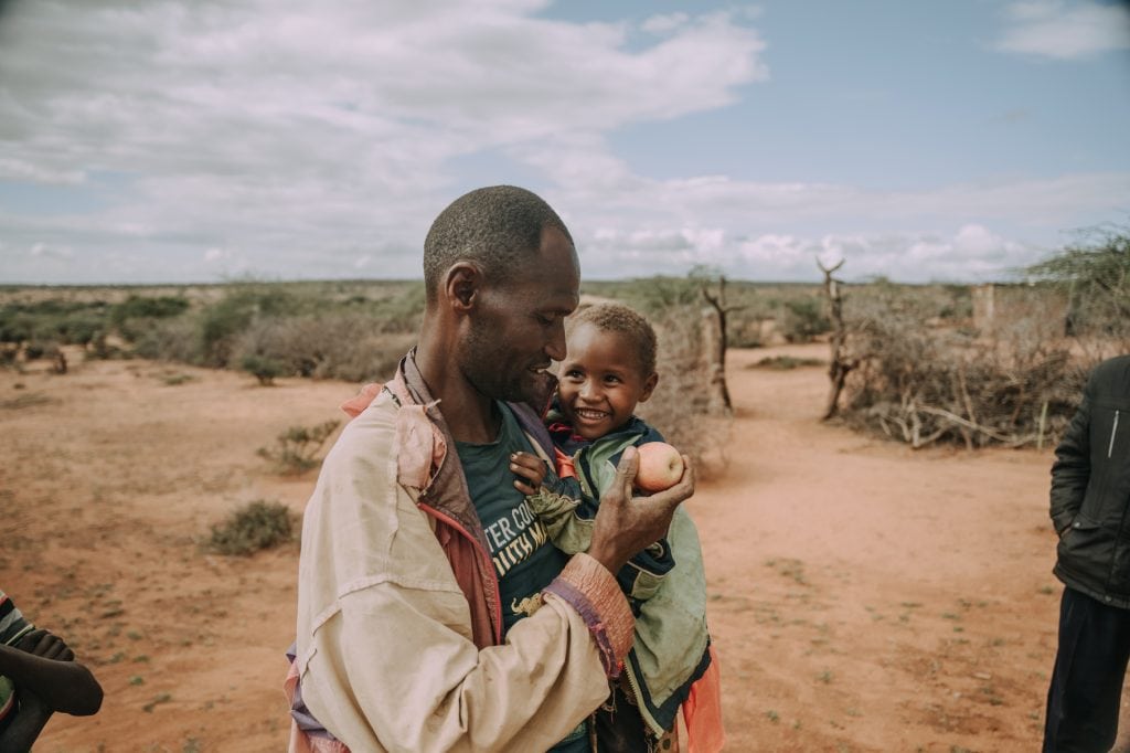 alt="Lebensmittelkrise, Nahrungsmittelkrise, weltweite Hungerkrise, Vater mit Junge auf Arm mit Apfel in Hand, Compassion Deutschland"