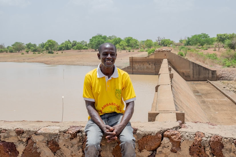 alt="Hunger kostet Würde, Jaques sitzt an einem Wasserdamm in Burkina Faso, Compassion Deutschland, Lebensmittelkrise"