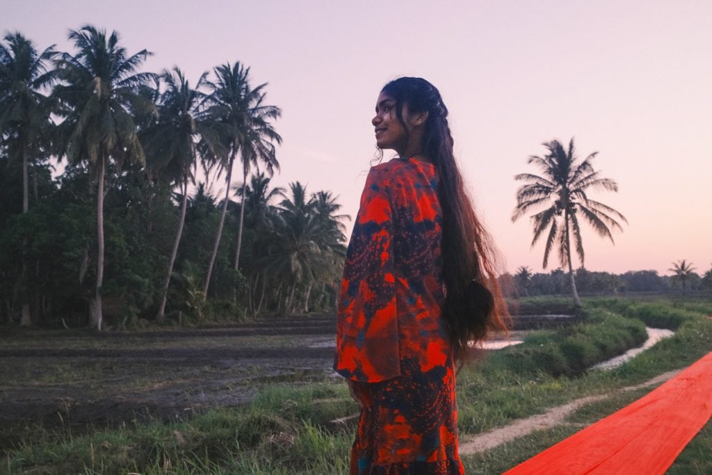 Mädchen auf einem roten Laufsteg zwischen Reisfeldern