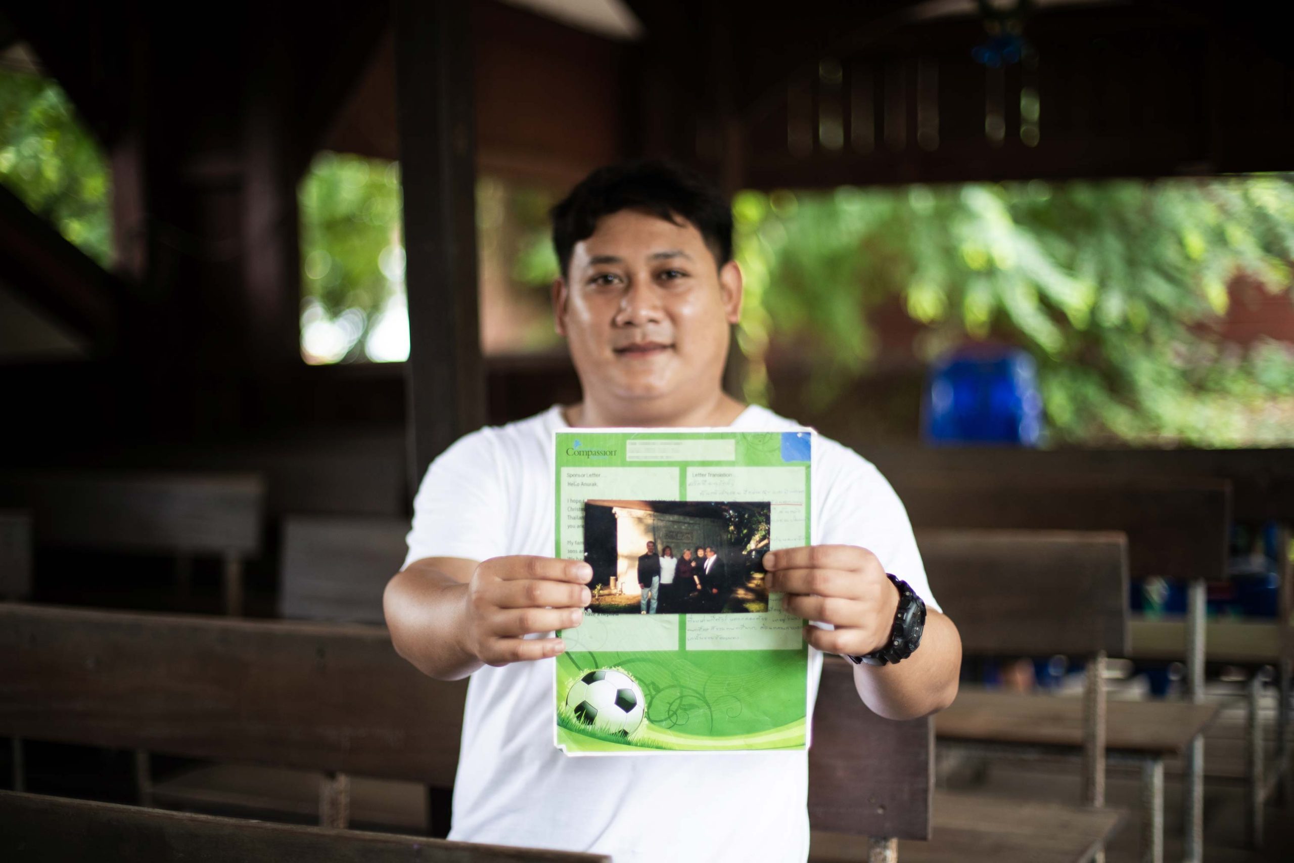 Wie Briefe ein Compassion-Patenkind ermutigen, Compassion Patenkind hält Brief in den Händen und lächelt