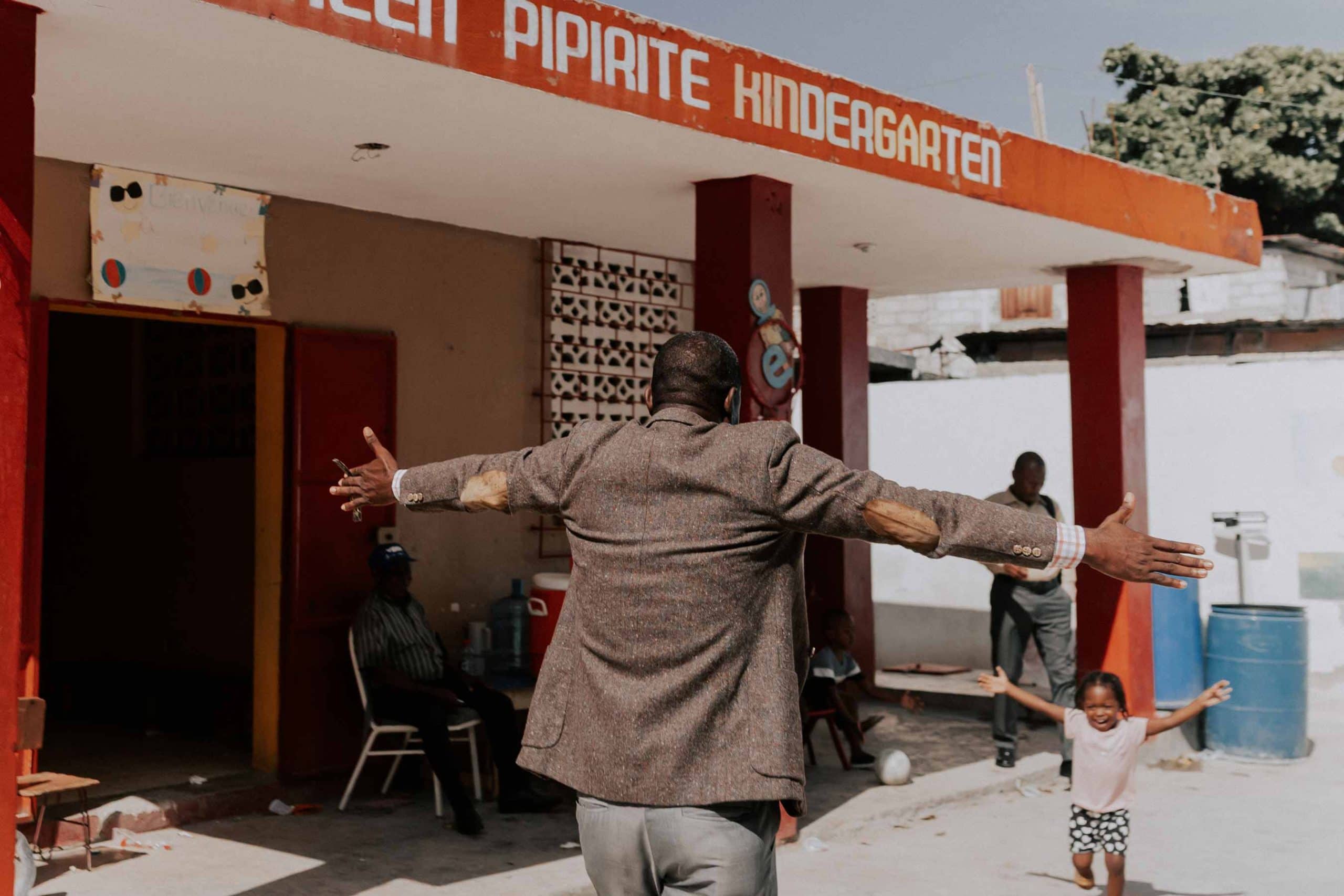 Pastor breitet die Arme aus und Kind läuft ihm entgegen in Haiti, Compassion Deutschland