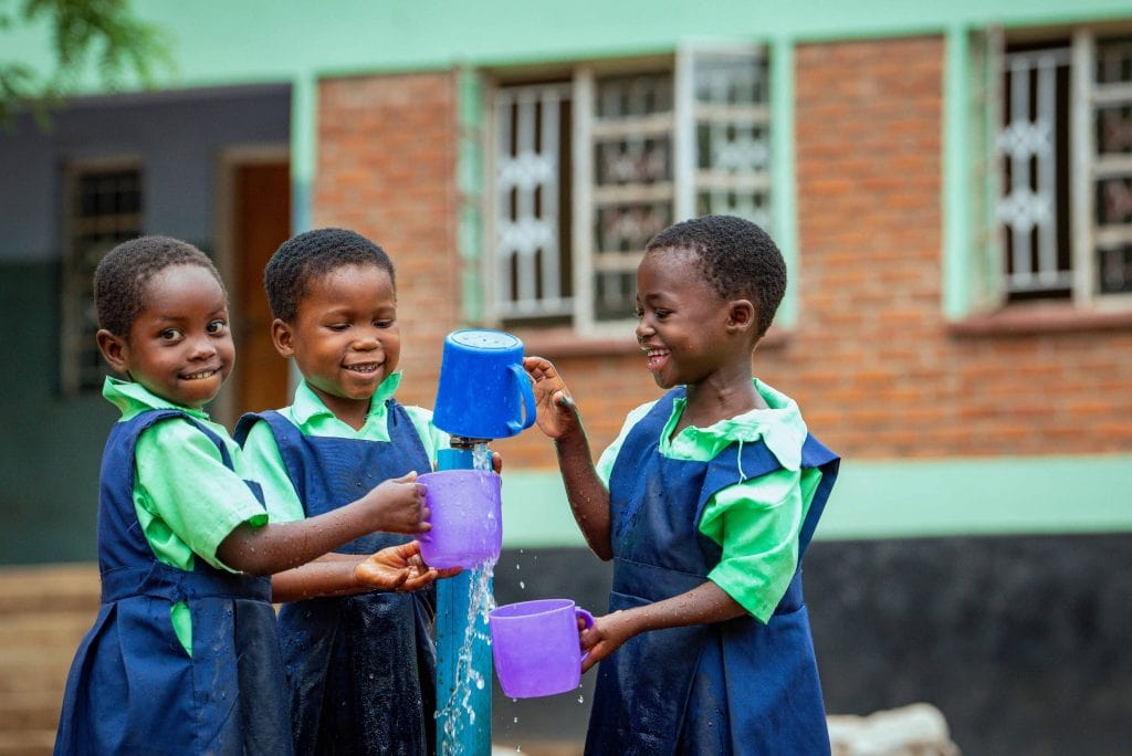 Kinder stehen an einem Brunnen, wenn Wasser zur Belastung wird, Compassion Deutschland