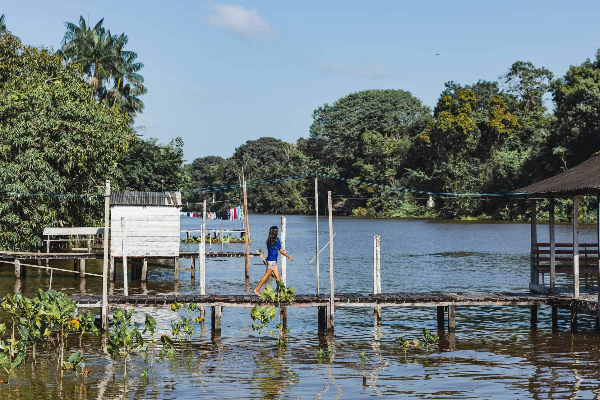 alt="Ein Mädchen läuft über einen Steg auf dem Wassser auf der Marajó-Insel am Amazonas, Compassion Deutschland"
