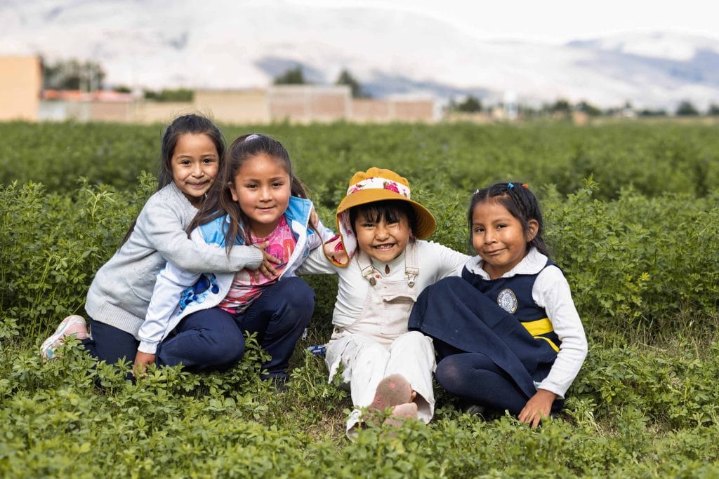 Kinder sitzen auf einer Wiese und lachen, Wie wir Kinder schützen wollen, Compassion Deutschland